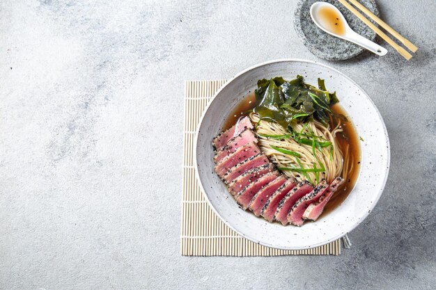 Japoński ramen Azjatycka zupa z makaronem ramen miso smażony stek z tuńczyka i algi morskie na białym tle