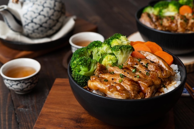 Japoński styl żywności Widok z góry na domowy kurczak Teriyaki grillowany z brokułami ryżowo-marchwiowymi na czarnej misce i na drewnianym stole