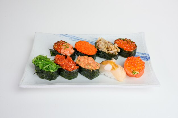 Japońskie sushi z rolkami wodorostów z Ikurą, Ebiko, Hotate, Wakame, Kurage na talerzu ceramicznym