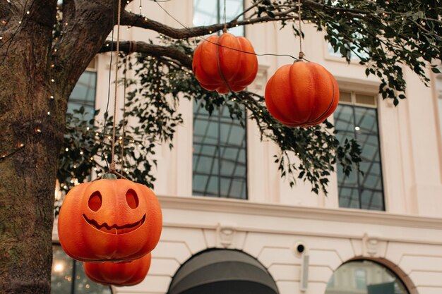 Jasna dynia z przerażającą twarzą Halloween wiszącą na drzewie z girlandami Tło na wakacje