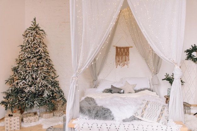 Zdjęcie jasna sypialnia w stylu skandynawskim ze świątecznym wystrojem i choinką