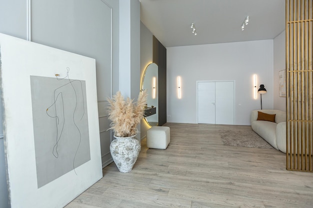 Jasne mieszkanie w nowoczesnym projekcie, lekkie ściany i drewniana podłoga, stylowy korytarz z pięknym wazonem i okrągłym lustrem.