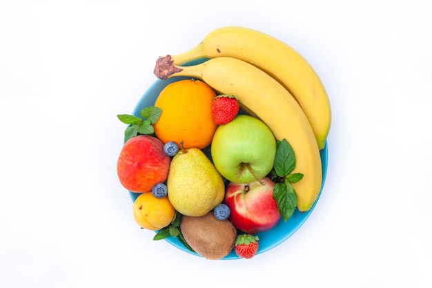 Jasne soczyste owoce ułożone w talerzu - jagody, banany, gruszki, jabłka, mięta