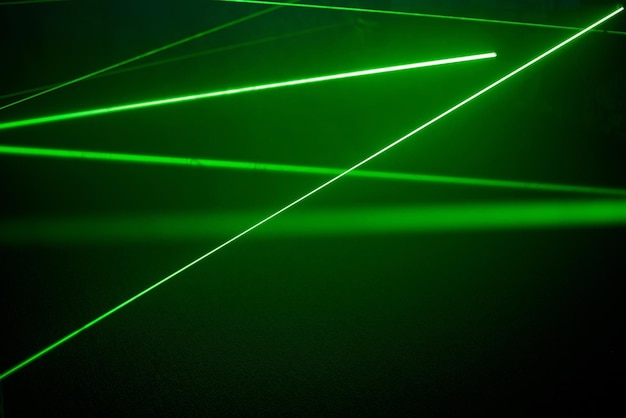 Jasne zielone światła laserowe neonowe oświetlają ciemność tworząc linie i kształty trójkątów w efekcie sci-fi