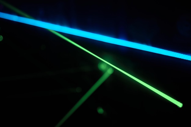 Jasne zielone światła laserowe oświetlają ciemność tworząc linie