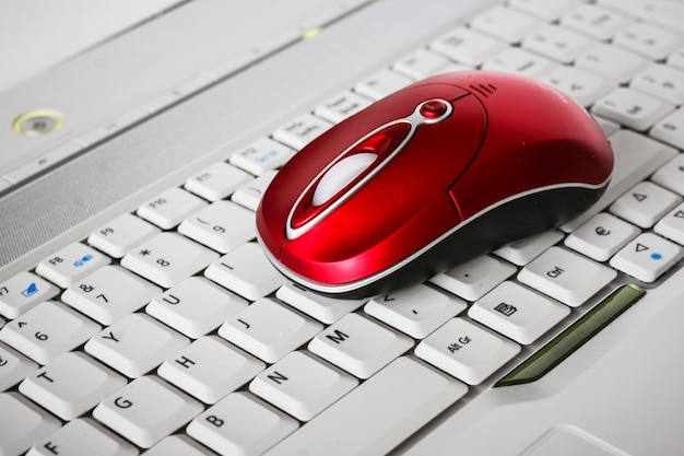 Jasnoczerwona bezprzewodowa mysz na białej klawiaturze laptopa