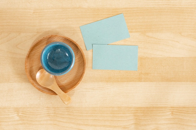 Jasnoniebieskie wizytówki obok jasnoniebieskiej miski na drewnianym stole Makieta wizytówek