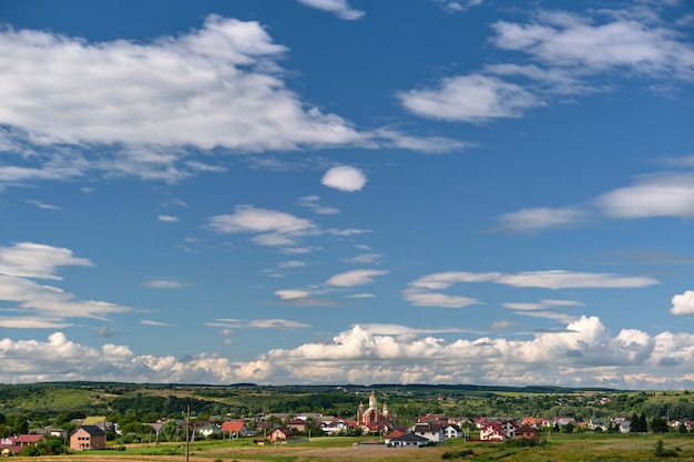 Jasny krajobraz białych chmur bufiastych cumulus na błękitne niebo nad obszarami wiejskimi.