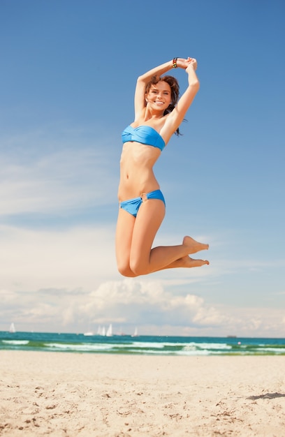 jasny obraz szczęśliwej skaczącej kobiety na plaży.