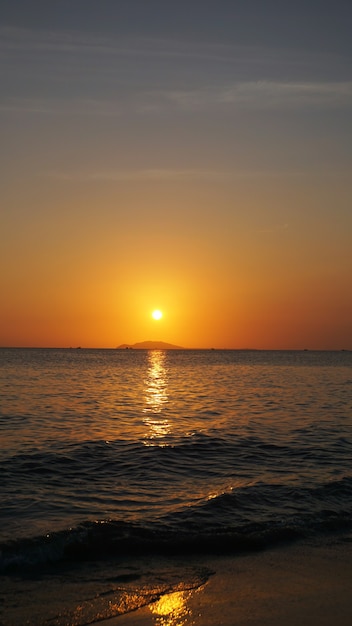 Jasny zachód słońca pod morzem z żółto-czerwonymi gradientowymi kolorami - pionowy
