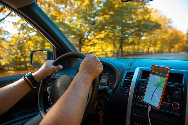 Jazda samochodem jesiennym lasem na nawigacja po stronie drogi w telefonie
