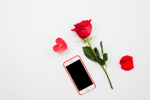 Jeden ciemny czerwony róża i telefon komórkowy na białym tle