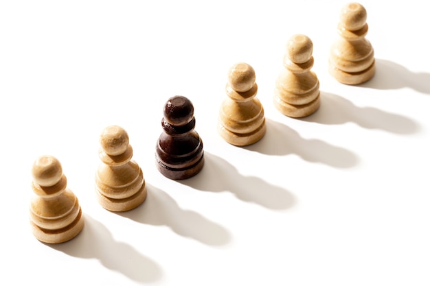 Zdjęcie jeden czarny pionek szachowy wśród białych. pojęcie rasizmu i dyskryminacji.