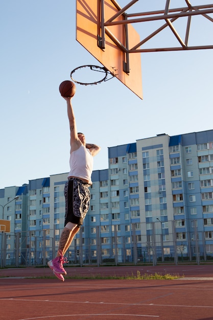 Jeden facet gra w koszykówkę na boisku sportowym.