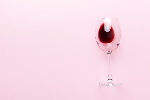Jeden kieliszek czerwonego wina podczas degustacji wina. Pojęcie czerwonego wina na kolorowym tle. Widok z góry, płaska konstrukcja.