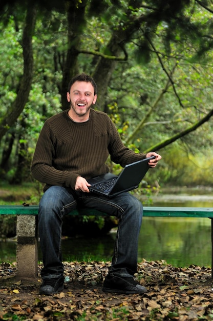 jeden młody biznesmen pracujący na laptopie na świeżym powietrzu z zieloną naturą w tle