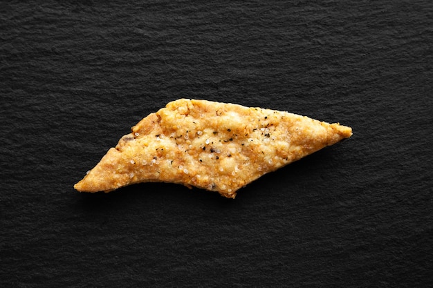 Zdjęcie jeden plik cookie z solą krakersy z serem na czarnym tle zdrowe domowe jedzenie