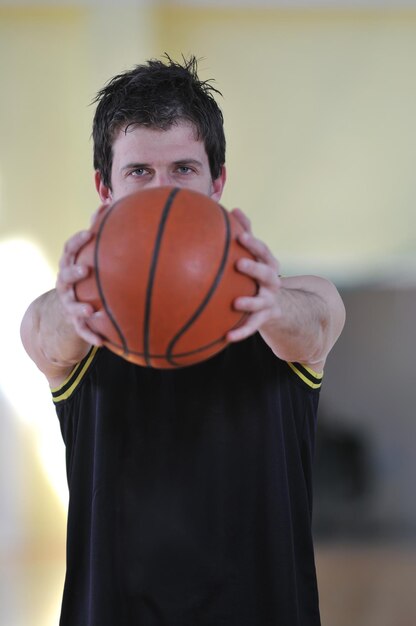 Zdjęcie jeden zdrowy młody człowiek gra w koszykówkę w szkolnej sali gimnastycznej