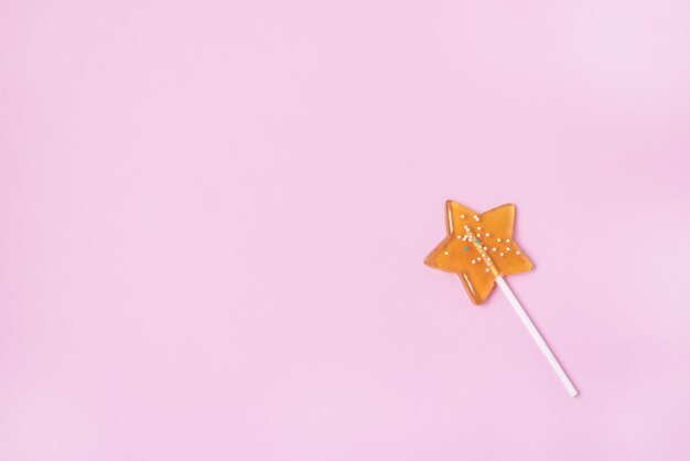 Jeden żółty lizak w kształcie gwiazdy na różowym pastelowym tle Koncepcja słodkich cukierków Widok z góry Przestrzeń kopii