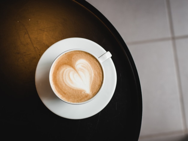 Jedna Filiżanka Cappuccino Z Latte Art Na Czarnym Stole, Biały Ceramiczny Kubek, Widok Z Góry. Kultura Kawiarniana.