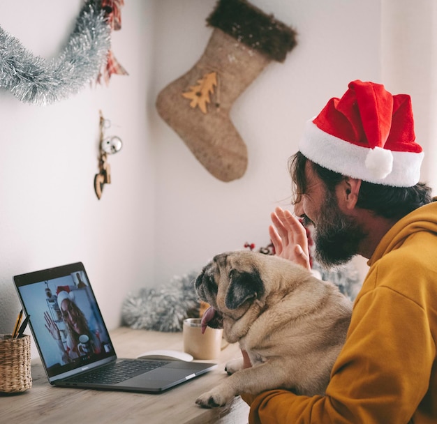 Jedna kobieta robi rozmowę wideo na laptopie ze swoim starym psem mopsem najlepszymi przyjaciółmi i szczęśliwą kobietą po drugiej stronie wyświetlacza połączenia z komputerem Zdalni przyjaciele podczas obchodów świąt Bożego Narodzenia