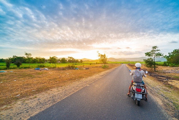 Jedna osoba na motocyklu, patrząc na widok gór w prowincji Phu Yen, Nha Trang Quy Nhon, przygoda podróżująca w Wietnamie. Widok z tyłu sunburst dramatyczne niebo o zachodzie słońca.