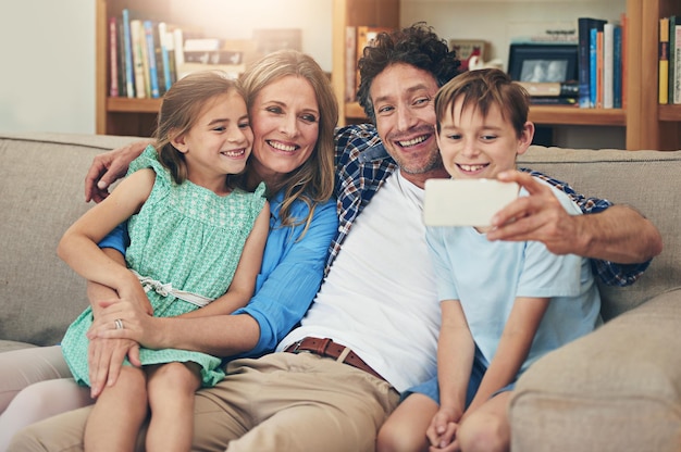 Jedna szczęśliwa zgryźliwa rodzina Ujęcie szczęśliwej rodziny robiącej selfie razem na telefonie komórkowym w domu