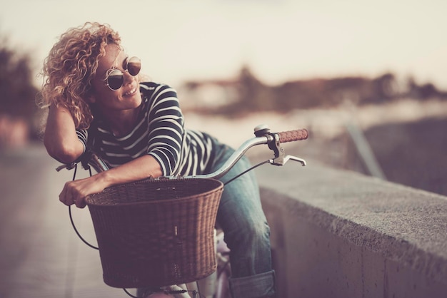 Jedna urocza kobieta uśmiecha się i cieszy się samotną rekreacją na świeżym powietrzu, relaksując się na rowerze Szczęśliwe kobiety uśmiechają się i wyglądają w okularach przeciwsłonecznych Zdrowy styl życia w transporcie zrównoważony rozwój ludzi