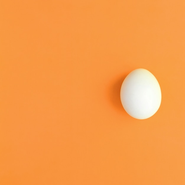 Jedno białe jajko na jasnym pomarańczowym