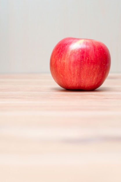 Jedno czerwone jabłko na drewnianym stole