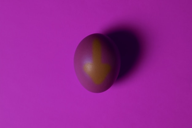 jedno fioletowe jajko na UV z narysowaną strzałką w dół