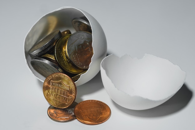 Jedno stłuczone białe jajko kurze i wypadają z niego amerykańskie centy