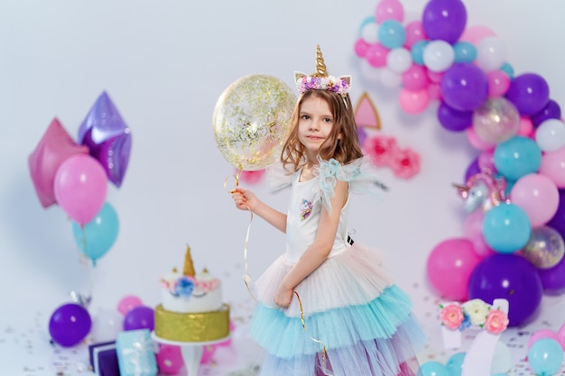 Jednorożec Dziewczyna trzyma balon złoty konfetti powietrza. Pomysł na dekorację przyjęcia urodzinowego w stylu jednorożca. Jednorożecowa dekoracja na imprezową dziewczynę