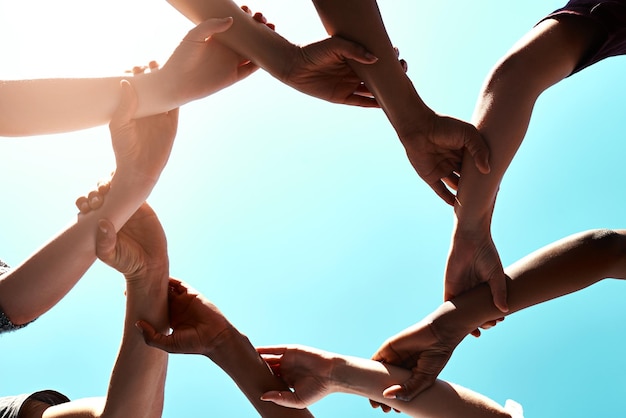 Jedność ramion i wsparcie z ludźmi na tle nieba na zewnątrz dla motywacji pracy zespołowej lub jedności Różnorodność współpracy i partnerstwa z grupą przyjaciół stojących razem w kręgu