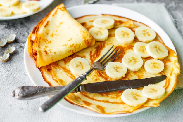 Zdjęcie jedzenie, deser, ciastka, naleśniki, ciasto. smakowici piękni bliny z bananem i miodem na betonowym tle