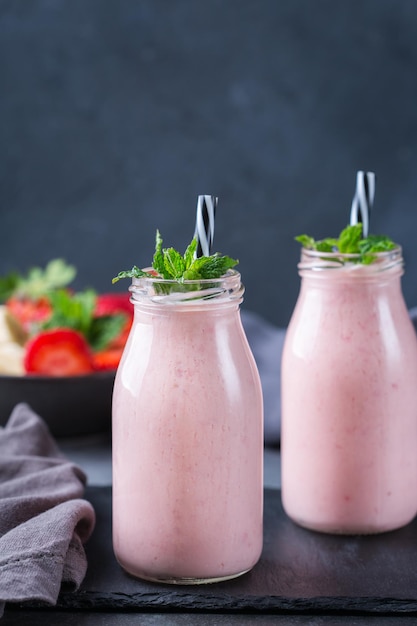 Jedzenie i picie, zdrowa dieta i odżywianie, styl życia, koncepcja wegańska, alkaliczna, wegetariańska. Różowy koktajl z bananem i truskawką na nowoczesnym stole w kuchni. Skopiuj tło przestrzeni