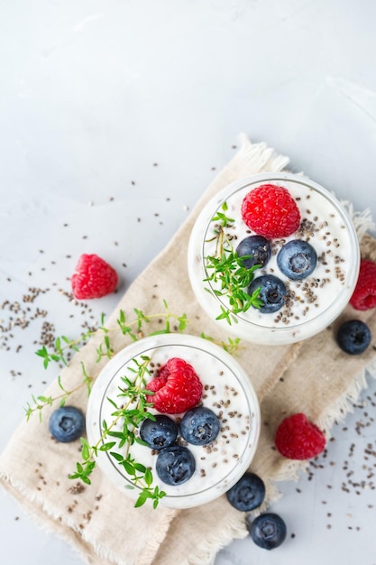 Jedzenie i picie zdrowe odżywianie i dieta koncepcja Domowy biały pudding chia ze świeżymi jagodami i zielonym tymiankiem na śniadanie na przytulnym stole kuchennym