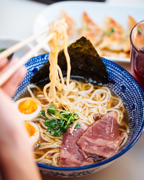 Jedzenie japońskiej zupy z makaronem ramen z jajkami pastrami na końcu