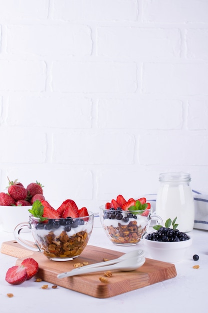 Jedzenie na śniadanie. Jogurt z jagodami, owocami i muesli w szklanych filiżankach. Copyspace