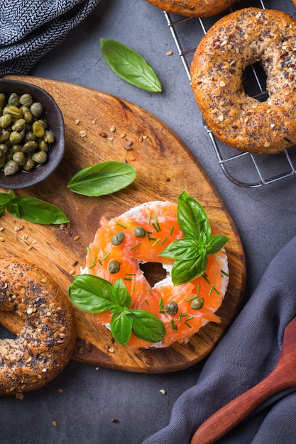 Jedzenie, obiad, brunch, posiłek na talerzu, koncepcja poszycia. Bajgle z wędzonym łososiem, twarożkiem i kaparami na stole. Płaskie świeckich, widok z góry tło.