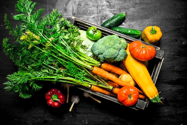 Jedzenie organiczne. Świeże warzywa w starym pudełku. Na czarnej tablicy.