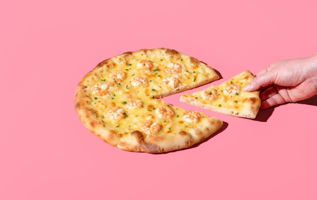 Jedzenie pizzy z krewetkami minimalistycznie na różowym tle Biorąc kawałek pizzy