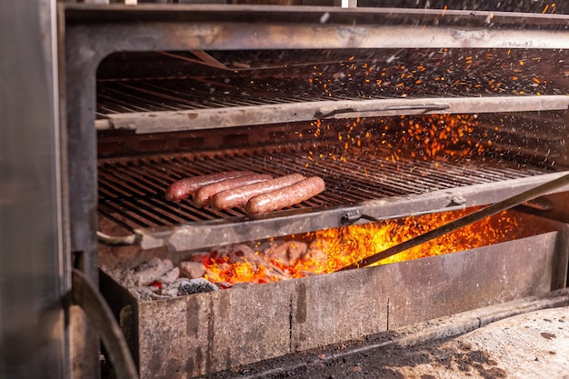 Jedzenie, pyszne i rzemieślnicza koncepcja - kiełbasa z grilla na płonącym grillu.