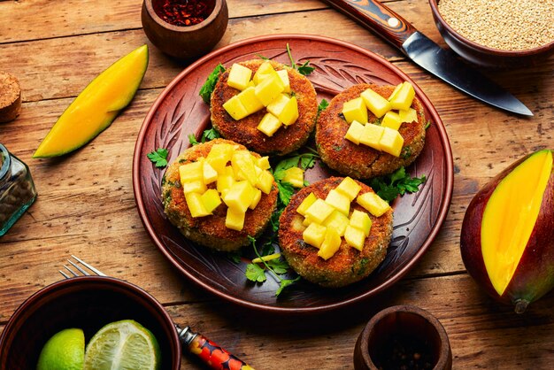 Jedzenie wegańskie, kotlet z komosy ryżowej przyozdobiony mango. Pieczony burger wegetariański