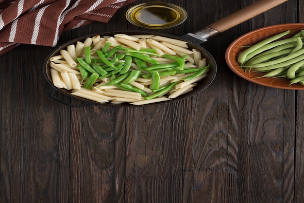 Jedzenie wegetariańskie. Makaron Penne z strąkami zielonej fasoli gotowany na patelni.
