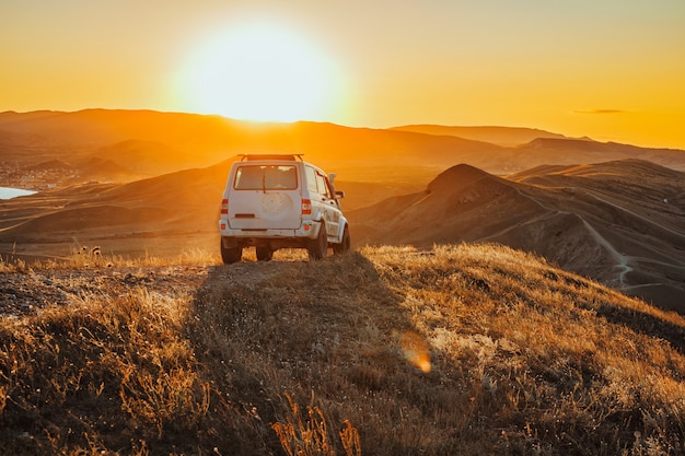 Jeep stoi na szczycie góry o zachodzie słońca Wspaniały krajobraz