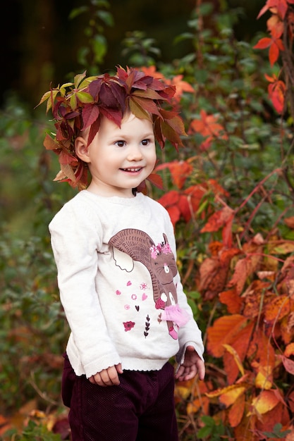Jesień emocjonalny portret dziewczynki. Całkiem mała dziewczynka z czerwonymi liśćmi winogron w jesiennym parku. Jesienne zajęcia dla dzieci. Halloween i Święto Dziękczynienia zabawa dla rodziny.
