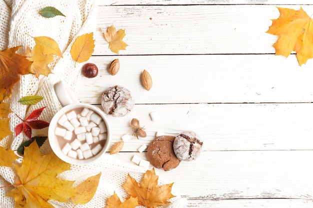 Jesienna kompozycja Ciemny szalik filiżanka kakao z piankami jesienne suche liście na białym drewnianym stole Widok z góry Kopiowanie miejsca