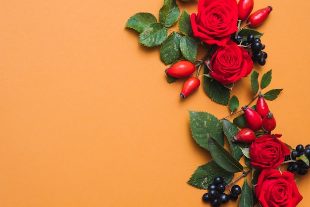 Jesienna kompozycja kwiatowa Czerwone jagody upadku, zielone liście i róże na pomarańczowo