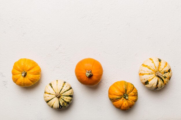 Jesienna kompozycja małych pomarańczowych dyni na kolorowym tle stołu Jesienna koncepcja Halloween i Święta Dziękczynienia Jesień płaska fotografia świecka Widok z góry z miejscem na kopię